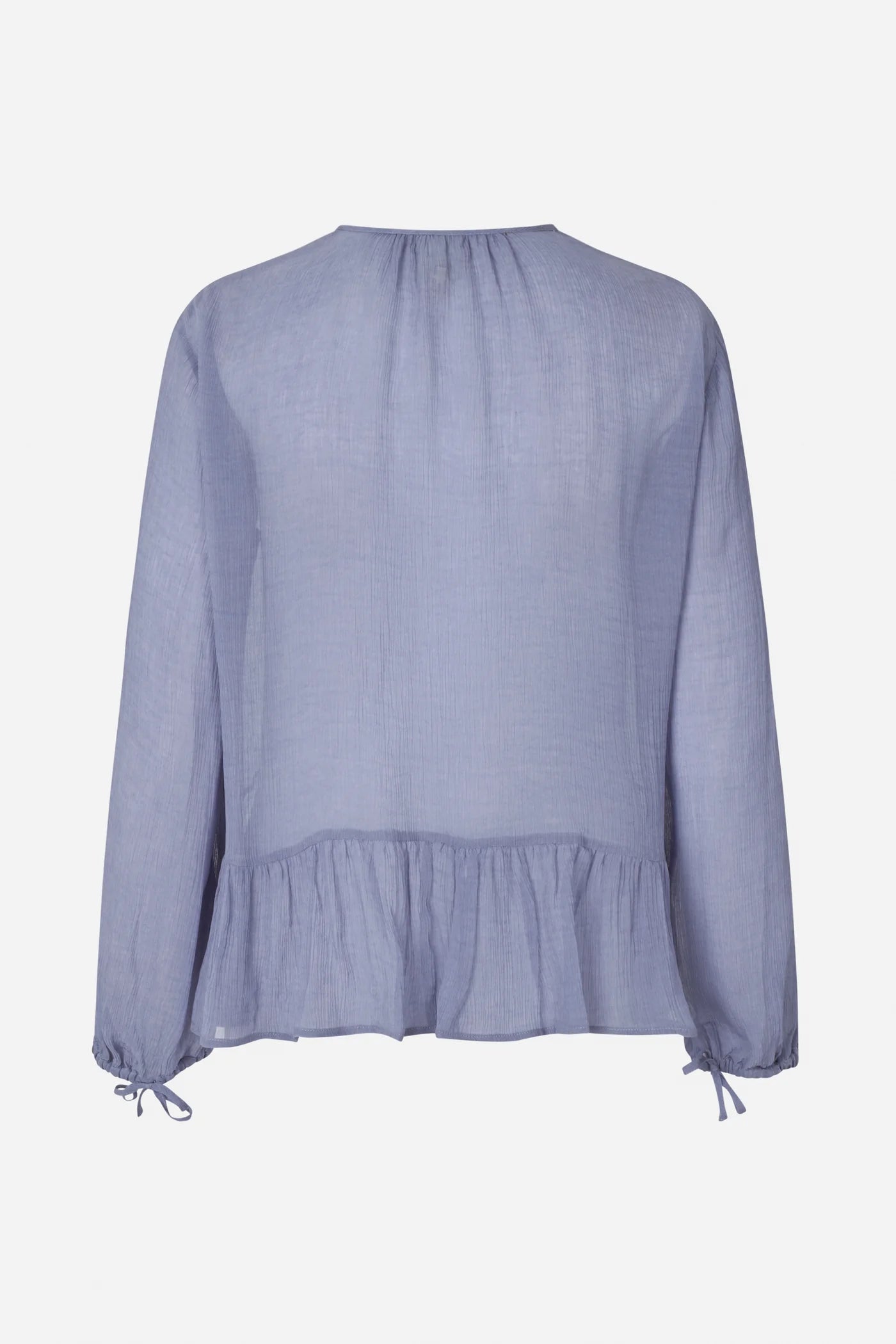 Auf dem Bild ist die Rückseite einer puderblauen Bluse auf weißem Hintergrund zu sehen. Die Bluse besteht aus leicht transparentem Stoff, hat lange Ärmel mit Schleifen an den Bündchen und einen leicht gerafften Volantsaum am unteren Rücken.