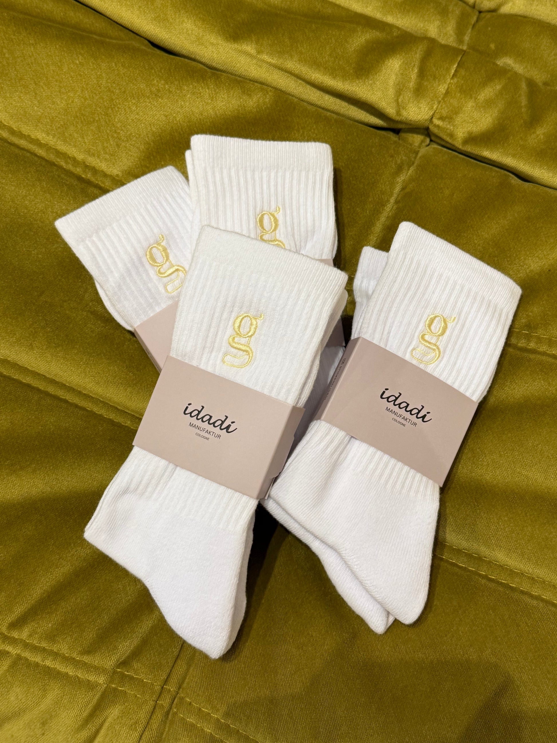 Tennissocken auf grünem Hintergrund. Auf den Socken ist ein gelbes G eingestickt.