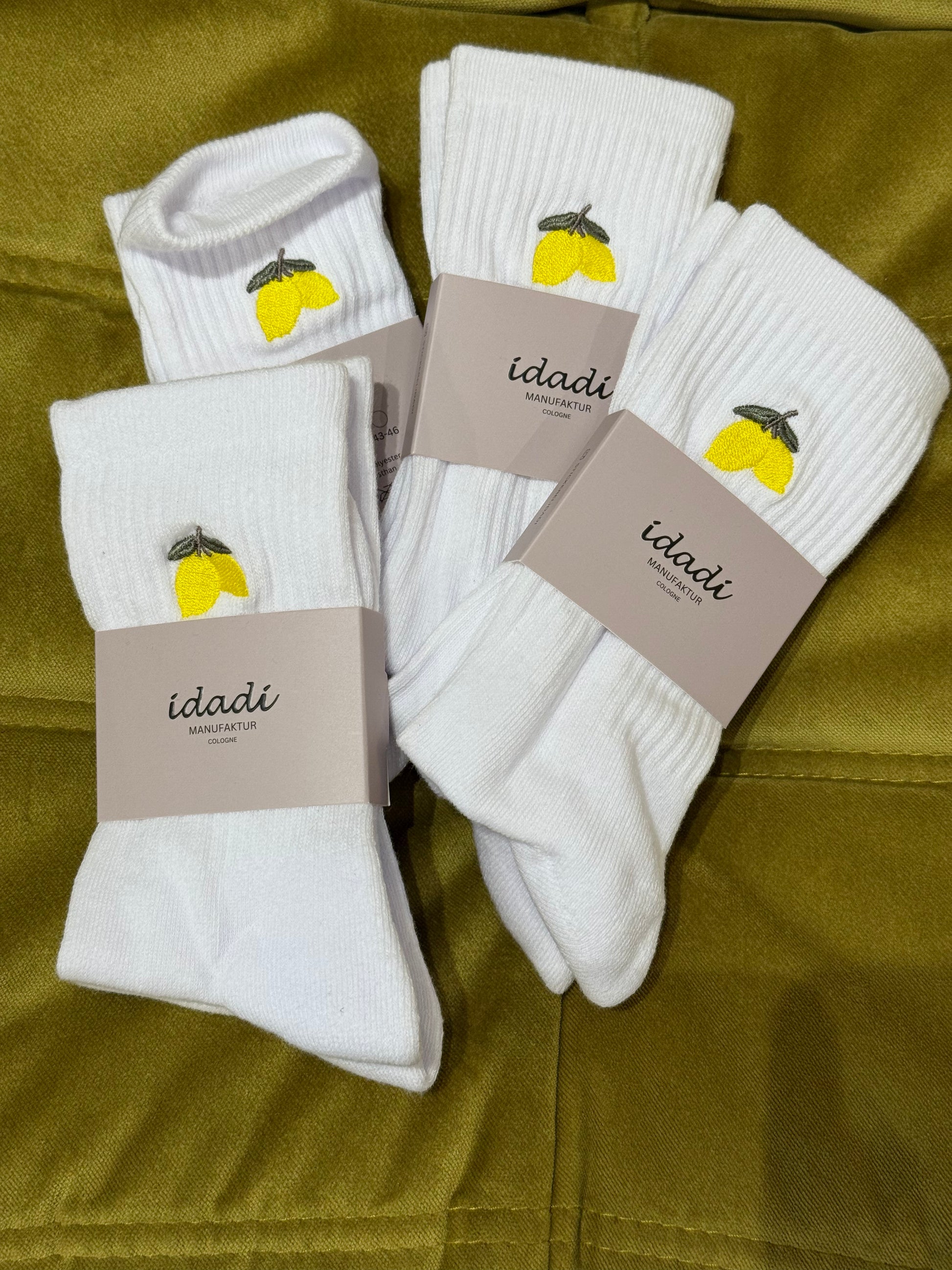 Tennissocken auf grünem Hintergrund. Auf den Socken sind Zitronen eingestickt.