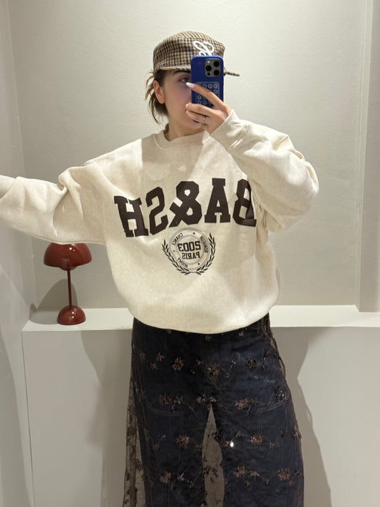 Frau macht Spiegelselfie, sie trägt eine Jeans mit Spitzenrock darüber und dazu einen beigen Sweater mit Ba&Sh Logo.