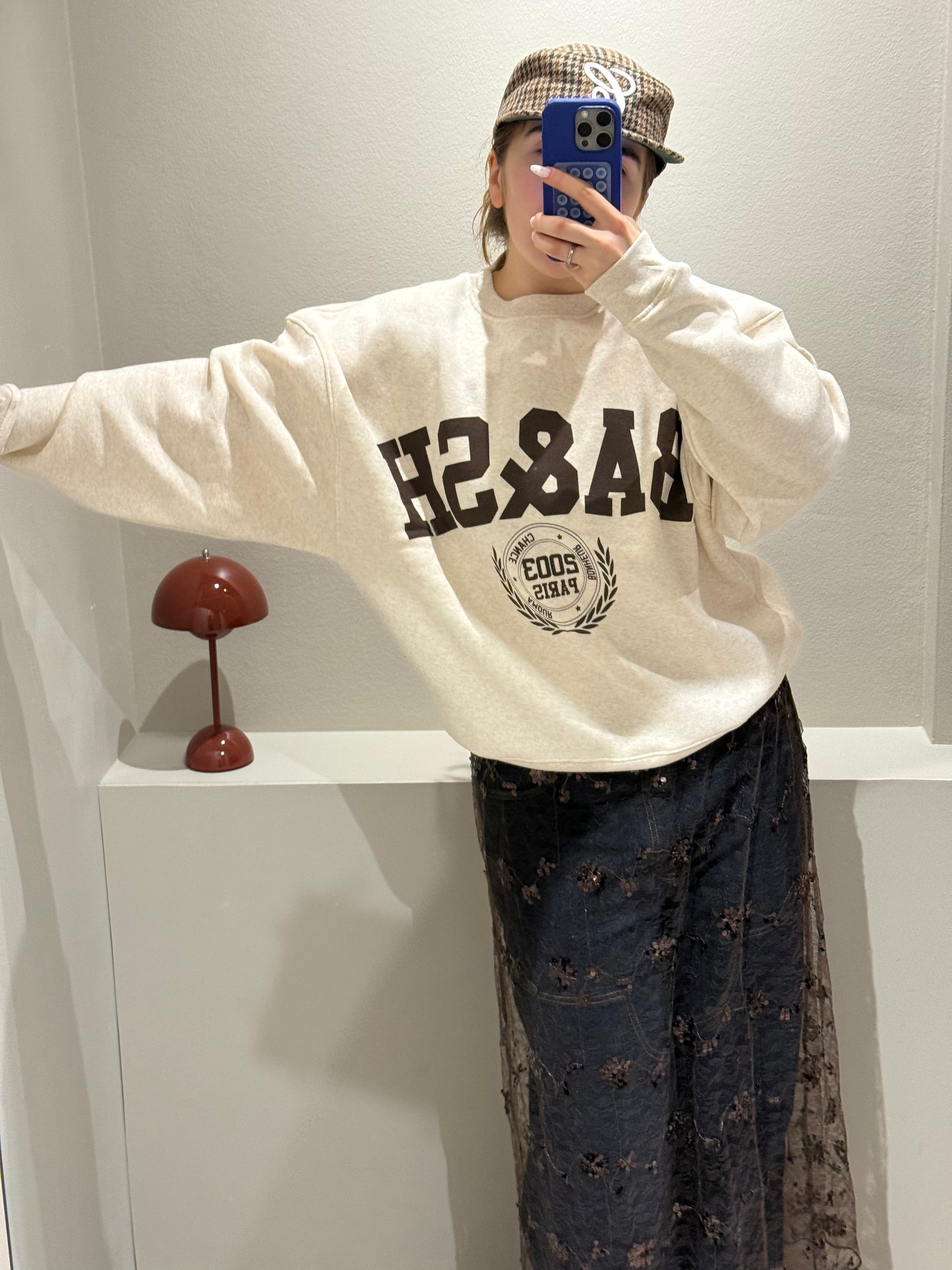 Frau macht Spiegelselfie, sie trägt eine Jeans mit Spitzenrock darüber und dazu einen beigen Sweater mit Ba&Sh Logo.