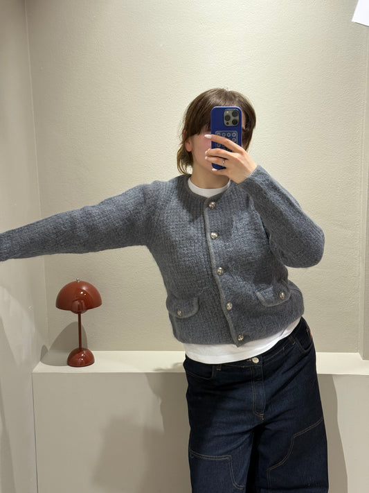 Frau macht Spiegelselfie sie trägt eine dunkle Jeans und grauen Cardigan mit Knöpfen.