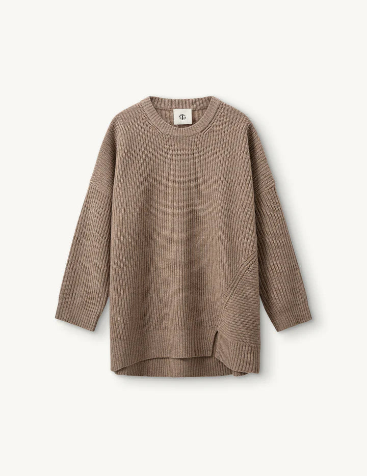 Beiger Strick mit kastigem Schnitt und Schlitzdetail vorne vor weißem Hintergrund.