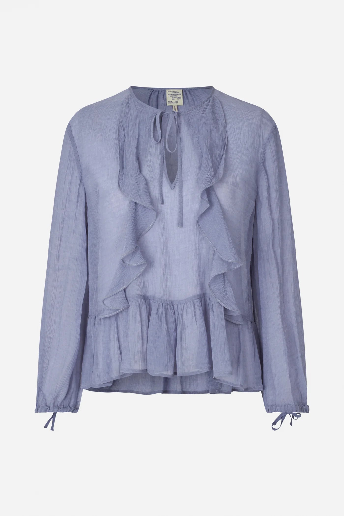 Auf dem Bild ist eine hellfliederfarbene Bluse zu sehen, die auf einem weißen Hintergrund liegt. Die Bluse hat große Volants auf der Vorderseite, einen runden Ausschnitt mit Bindeband und lange Ärmel mit Schleifen an den Bündchen.