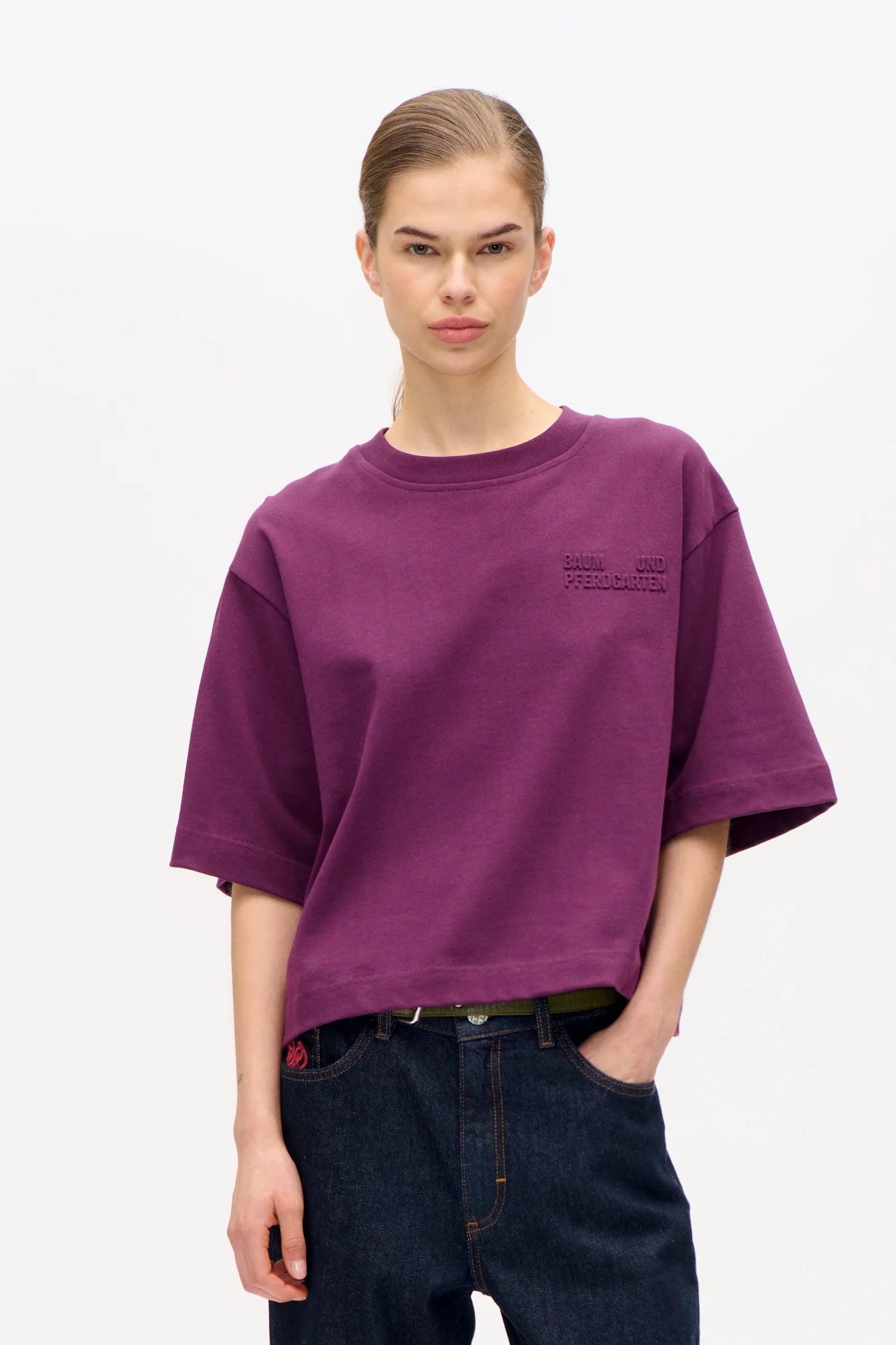 Bild von Frau, sie trägt ein kastiges Tshirt in Plum mit dunkler Jeans.