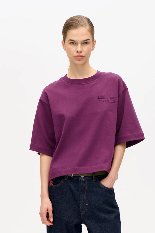 Bild von Frau, sie trägt ein kastiges Tshirt in Plum mit dunkler Jeans.