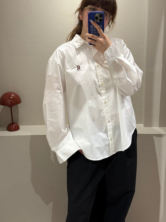 Frau macht Spiegelselfie, im Fokus ist eine weiße Bluse mit aufgesticktem G-Logo.
