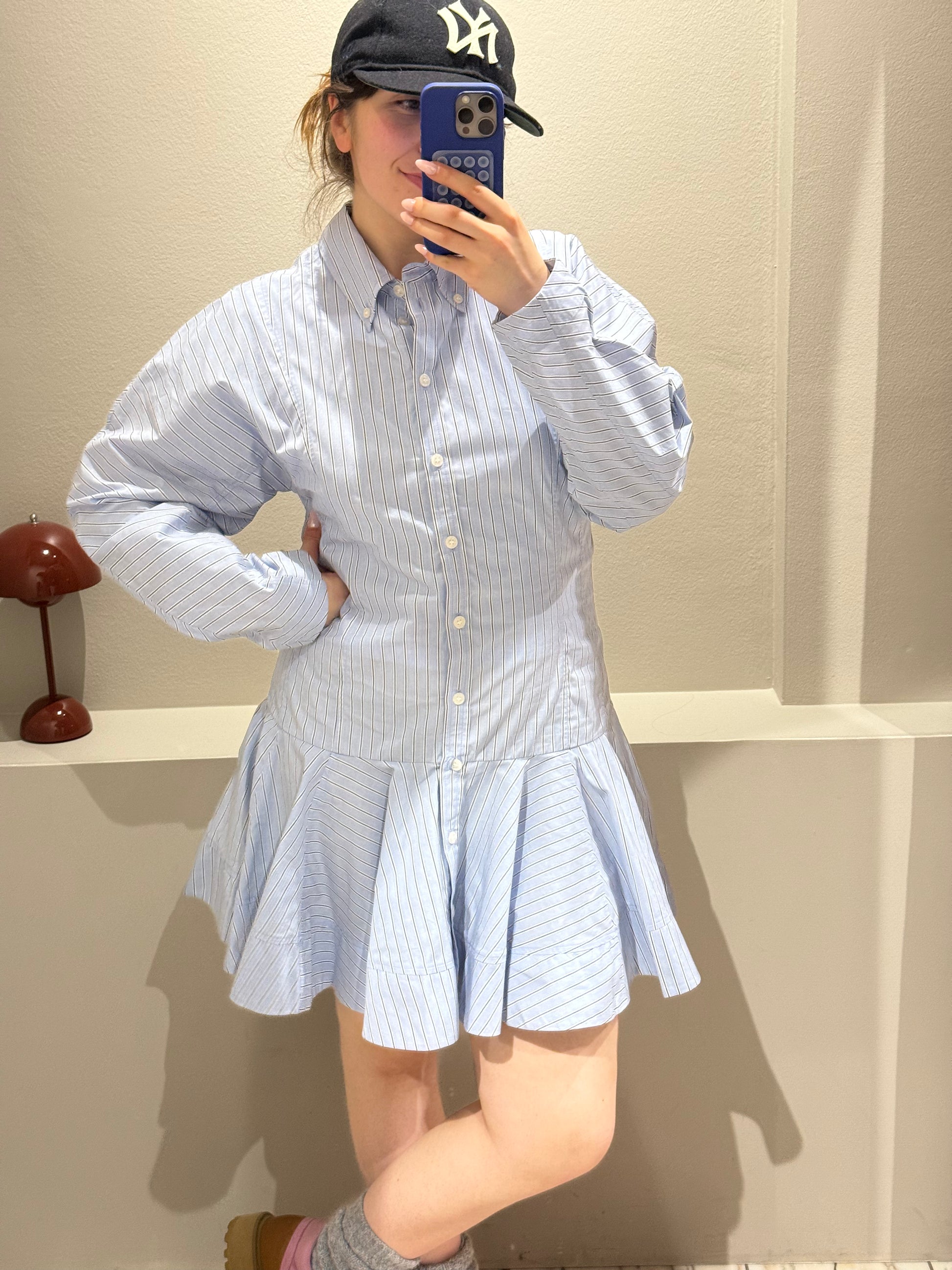 Frau macht Spiegelselfie sie trägt ein gestreiftes Blusenkleid mit Rüschenrock.