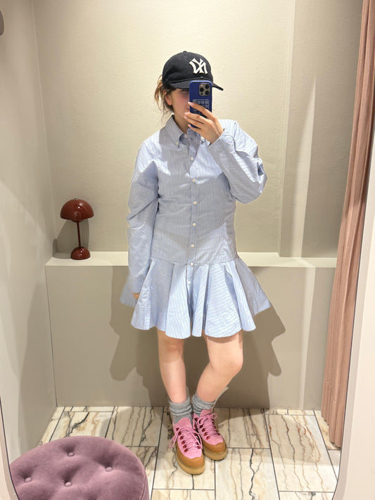 Frau macht Spiegelselfie sie trägt ein gestreiftes Blusenkleid mit Rüschenrock.