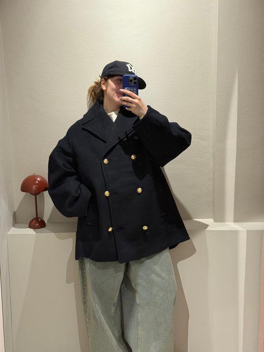 Frau macht Spiegelselfie, sie trägt eine dunkelblaue Cabanjacke und Jeans.