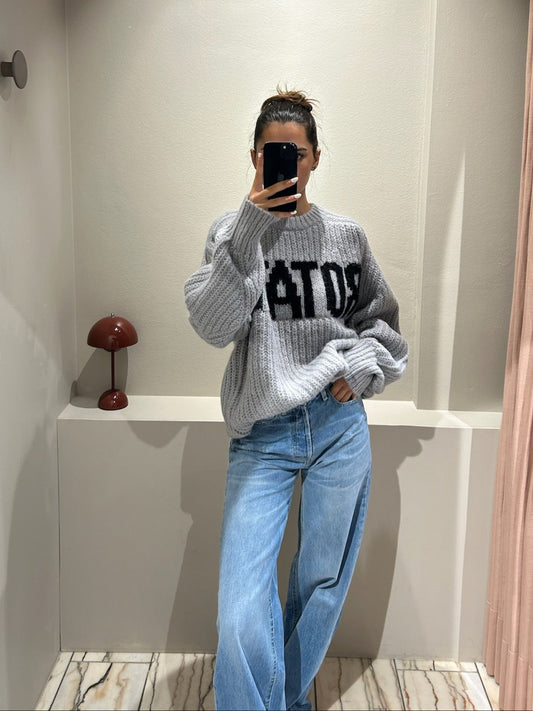 Frau macht Spiegelselfie, sie trägt Jeans und einen grauen kastigen Strickt mit Rotate Schriftzug.