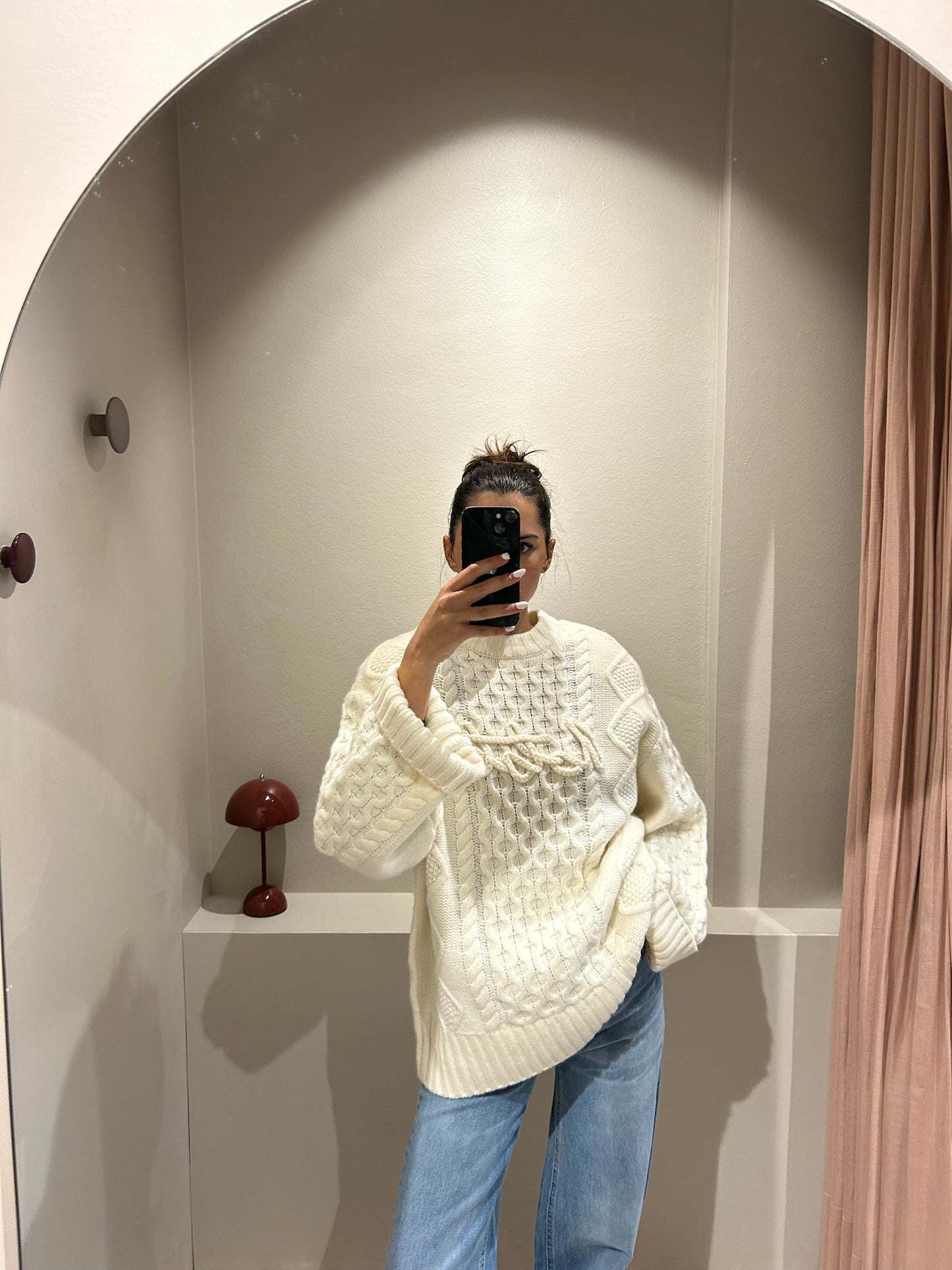 rau macht Speigelselfie, sie trägt einen kastigem weißen Cable Knit Sweater und Jeans.