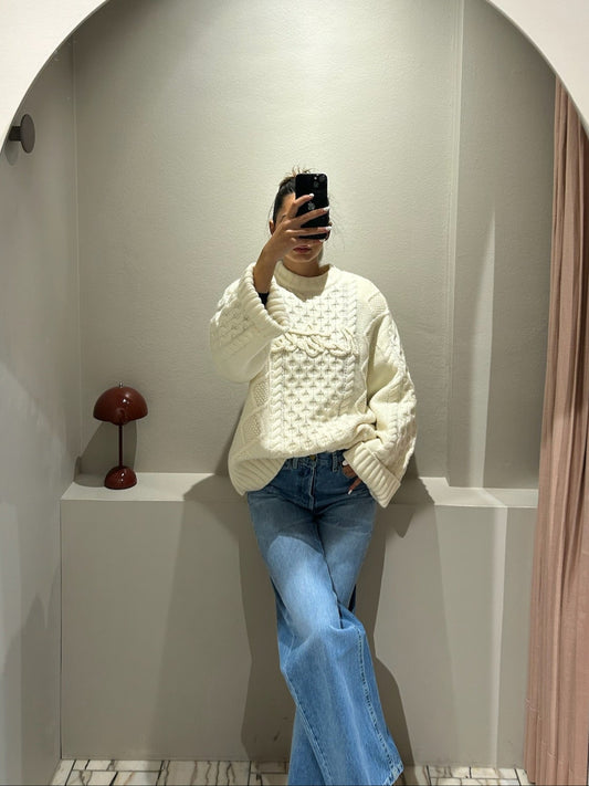 Frau macht Speigelselfie, sie trägt einen kastigem weißen Cable Knit Sweater und Jeans.