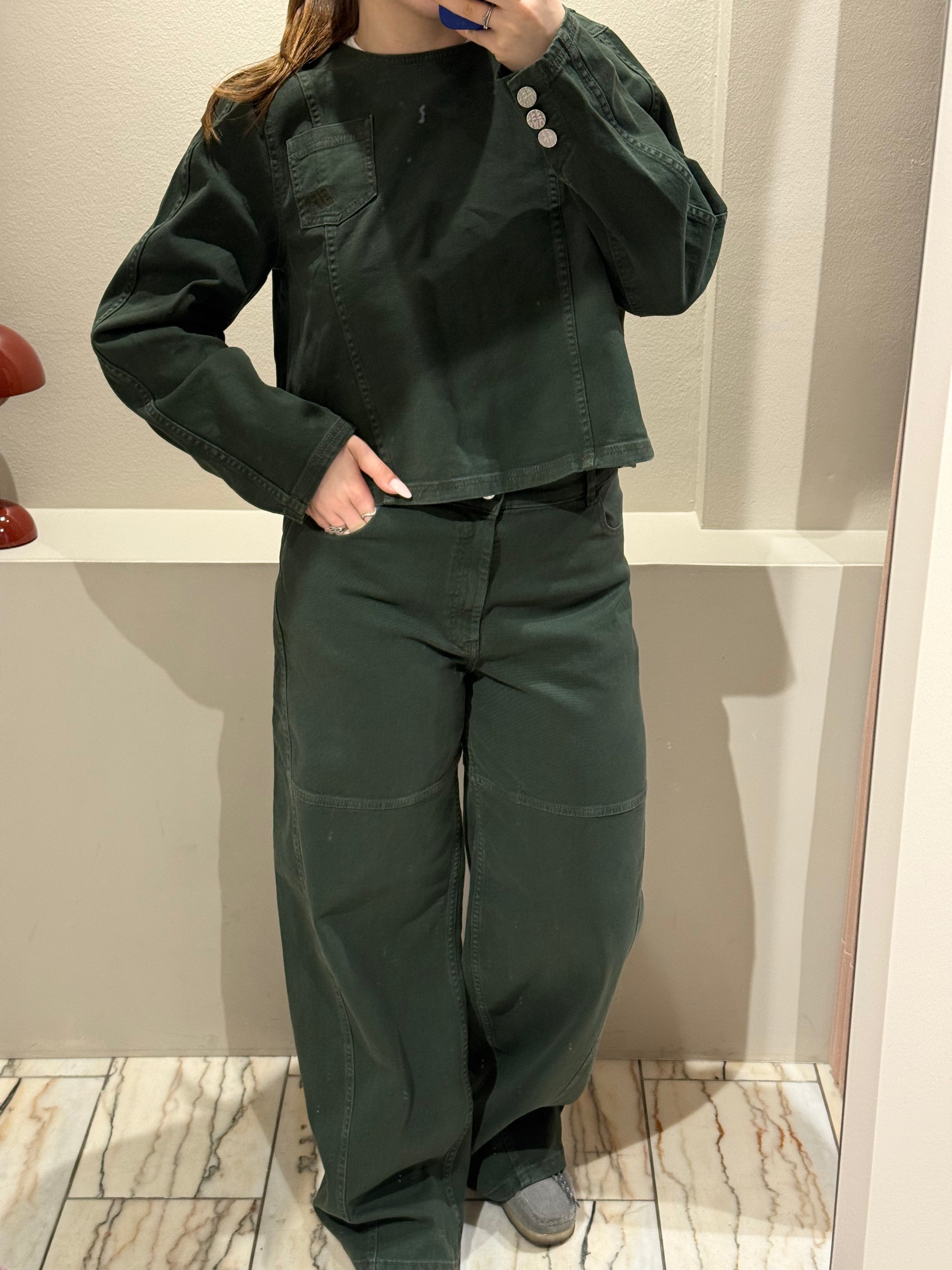 Frau macht Spiegelselfie in grünem Jenas Outfit bestehend aus Bluse und weiter Jeans.