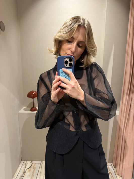 Frau macht Spiegelselfie, sie trägt schwarze Hose und schwarze transparente Bluse.