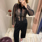 Frau macht Spiegelselfie, sie trägt schwarze Hose und schwarze transparente Bluse.