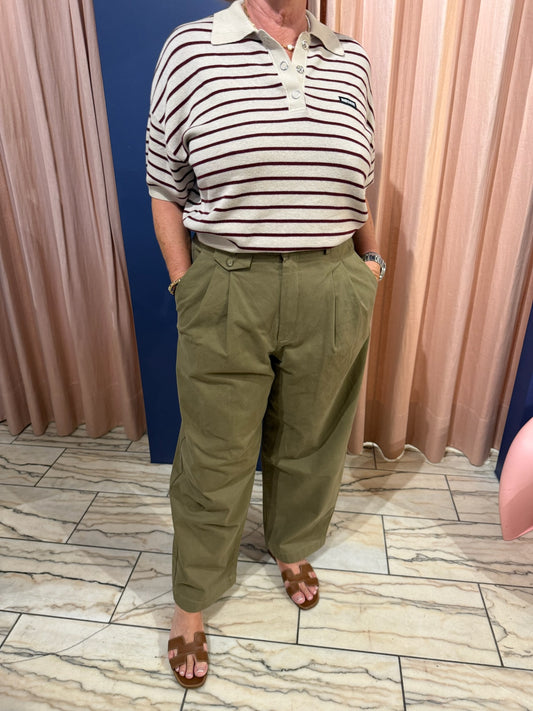 Bild von einer Frau, sie trägt eune Grüne Bundfaltenhose mit weitem Bein und ein gestreiftes Polo.