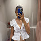 Eine Frau macht ein Spiegel Selfie, sie trägt eine weiße Kurzarmbluse mit Voilants und sie ist leicht transparent.