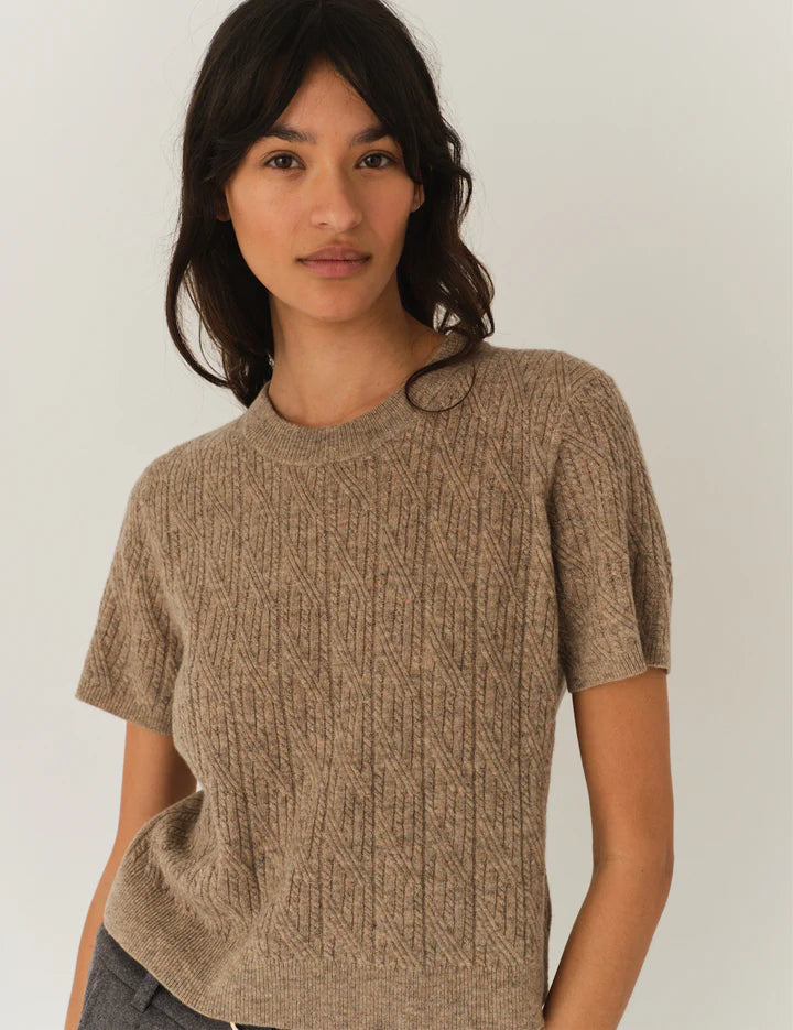 Frau vor weißem Hintergrund, sie trägt ein gestricktes Tshirt in beige.