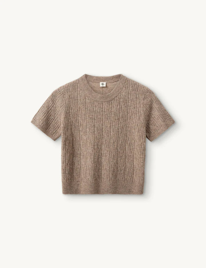 Beiges gestricktes Tshirt vor weißem Hintergrund.